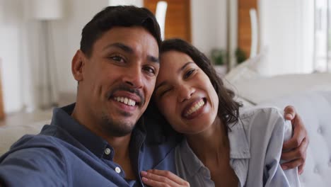 Porträt-Eines-Glücklichen-Hispanischen-Paares,-Das-Sich-Auf-Dem-Sofa-Im-Wohnzimmer-Umarmt