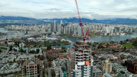 Tower Crane On The Tower Building Under Construction With Cityscape In The Background In BC, Canada. - aerial shot
