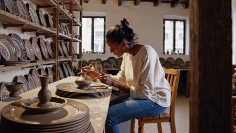 woman painting pottery in a workshop