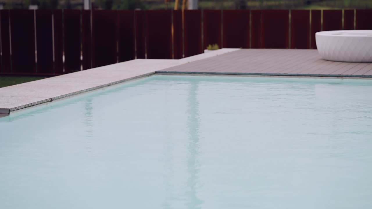 Rolig stemning ved poolen, himlen spejler sig i vandet, omkranset af et elegant design