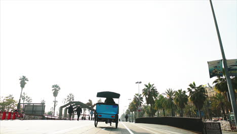 summer in platja de la barceloneta, la barceloneta beach. people and tourists walking by, pedicabs passing by.