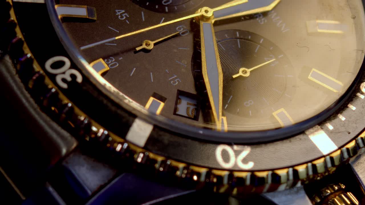Close up of an elegant wristwatch with a smooth zoom out revealing golden details under warm indoor lighting