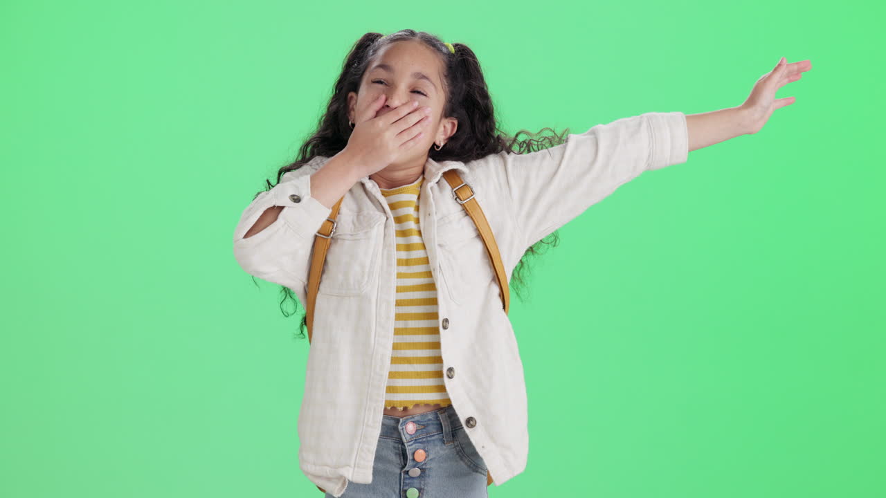 A happy schoolgirl poses in front of a green screen
