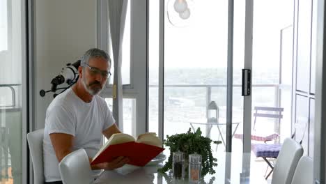 Man-reading-book-while-eating-breakfast-on-table-4k