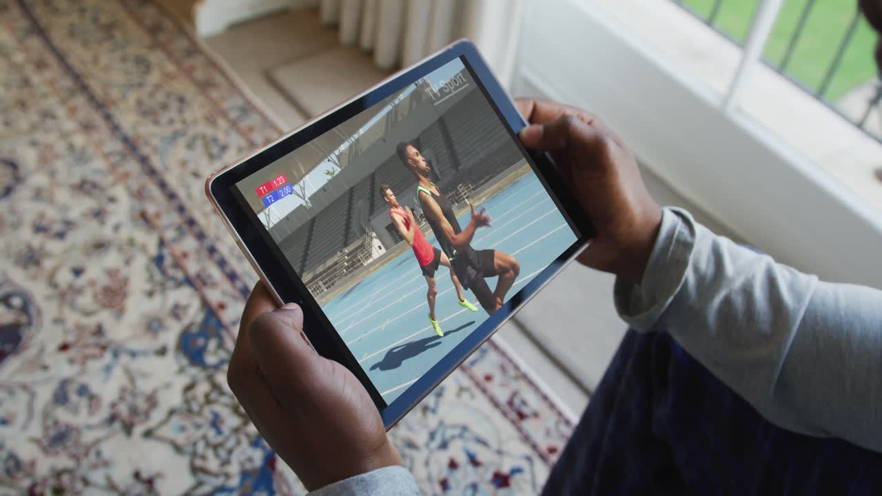 Composite of man sitting at home watching athletics running event on tablet