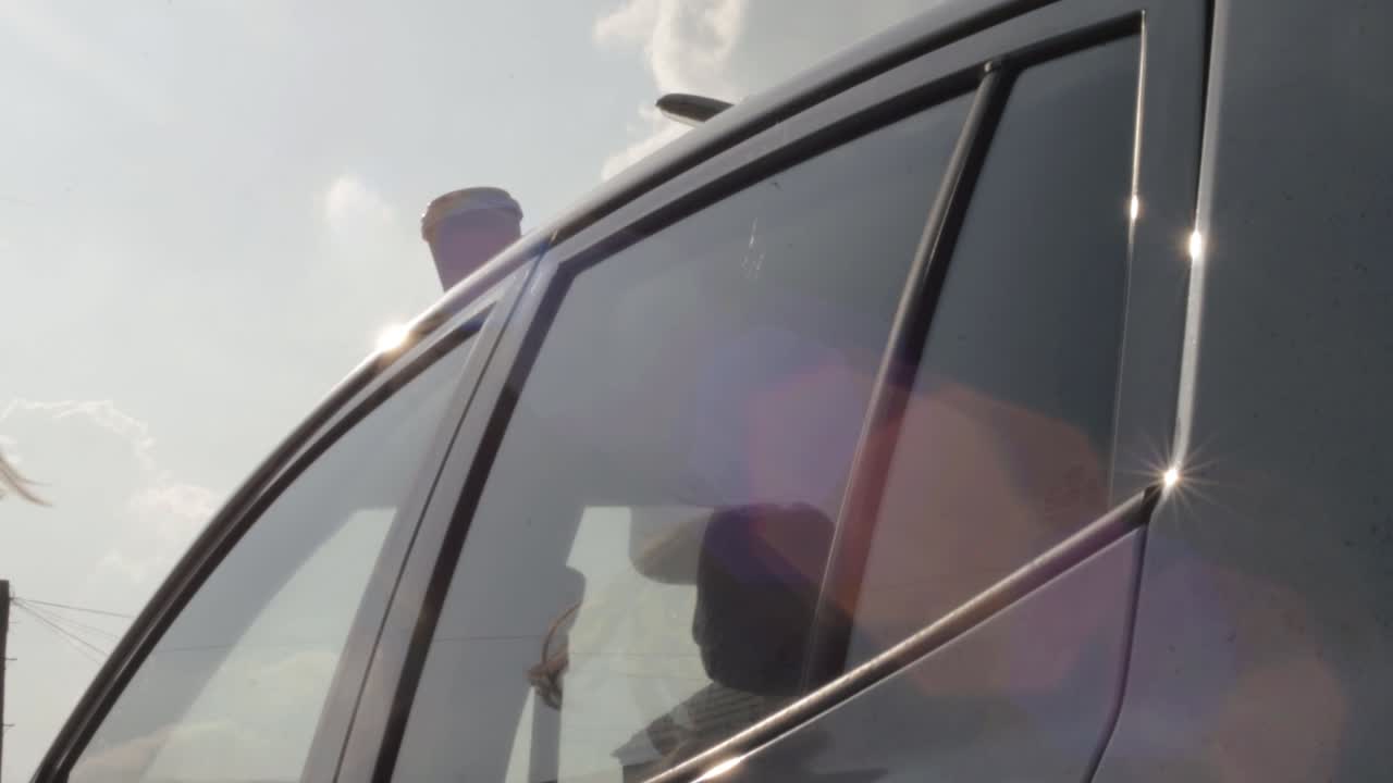 차 지붕에 커피 테이크아웃을 놓고 문을 여는 여자