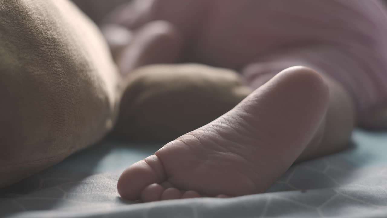 Handheld close up of baby girl foot while sleeping on bed at home