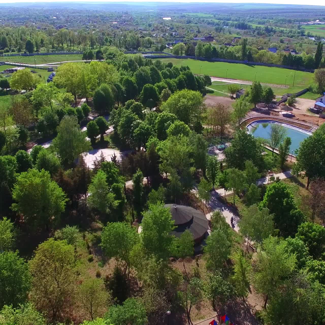 Beautiful green city park with artificial pond in the middle. Acres of greenery and walking paths from birds' eye view