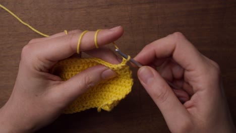 top shot of a female holding a piece of yellow wool and a needle