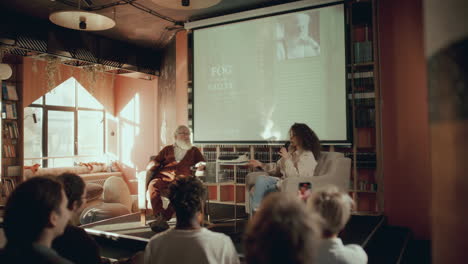 autora anciana y moderadora presentando un libro a la audiencia en la biblioteca