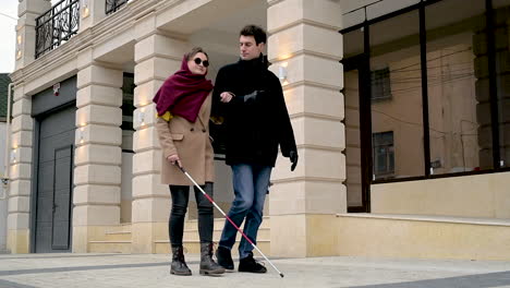 bottom view of a man and a blind woman walking in the street