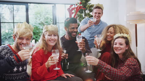 portrait of friends celebrating with champagne after christmas dinner making a toast to camera