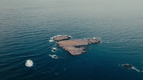 reine, lofoten islands, norway - a small rocky islet surrounded by deep blue waters - aerial drone shot