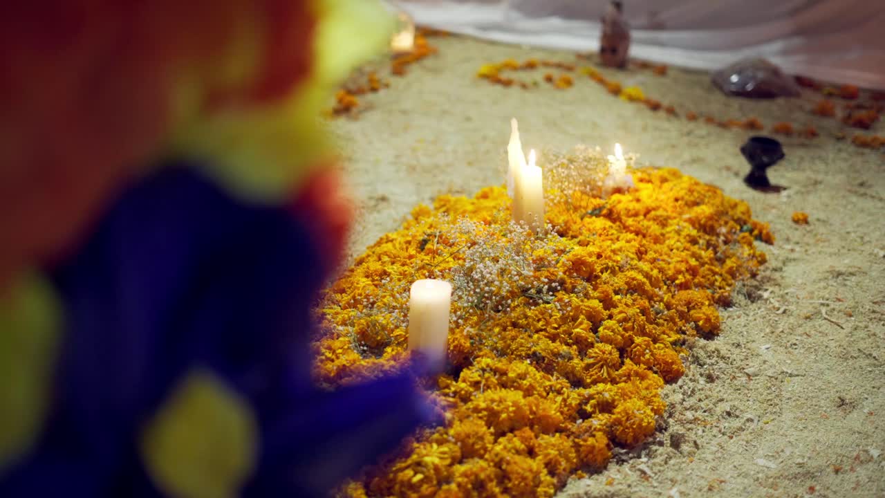Close-up of Día de los Muertos altar covered in marigolds and candles glowing at night during the traditional celebration