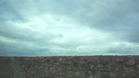 moving along a stone wall with a cloudy sky