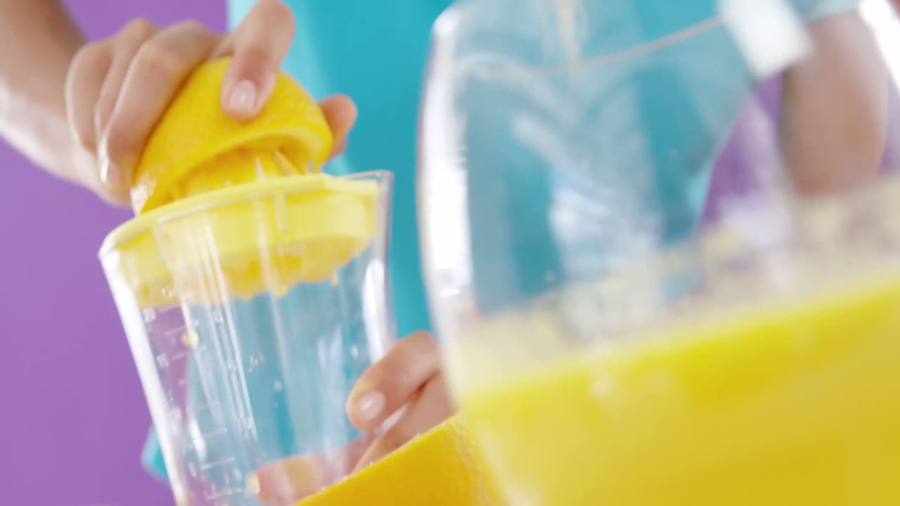 보라색 배경 에 대해 주스기 에서 달 ⁇ 한 라임 주스 를 준비 하는 여자