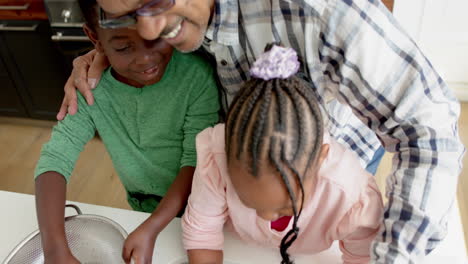 Happy-african-american-grandparents-and-grandchildren-washing-vegetables-in-kitchen,-slow-motion