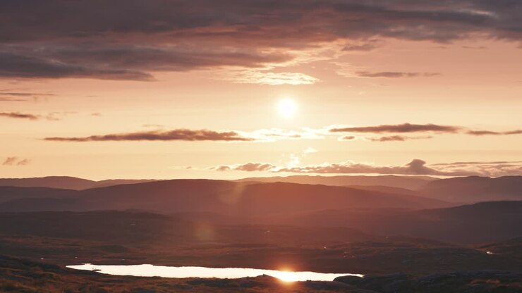 El sol de medianoche se posa en el horizonte proyectando una luz cálida sobre el paisaje