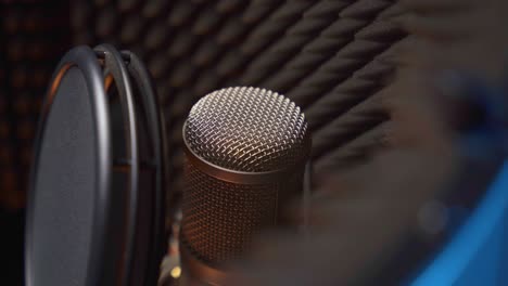 primer plano de un micrófono de estudio con protección contra explosiones y pantalla de sonido a su alrededor