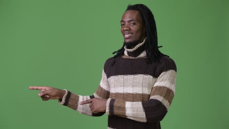 young handsome african man with dreadlocks against green background