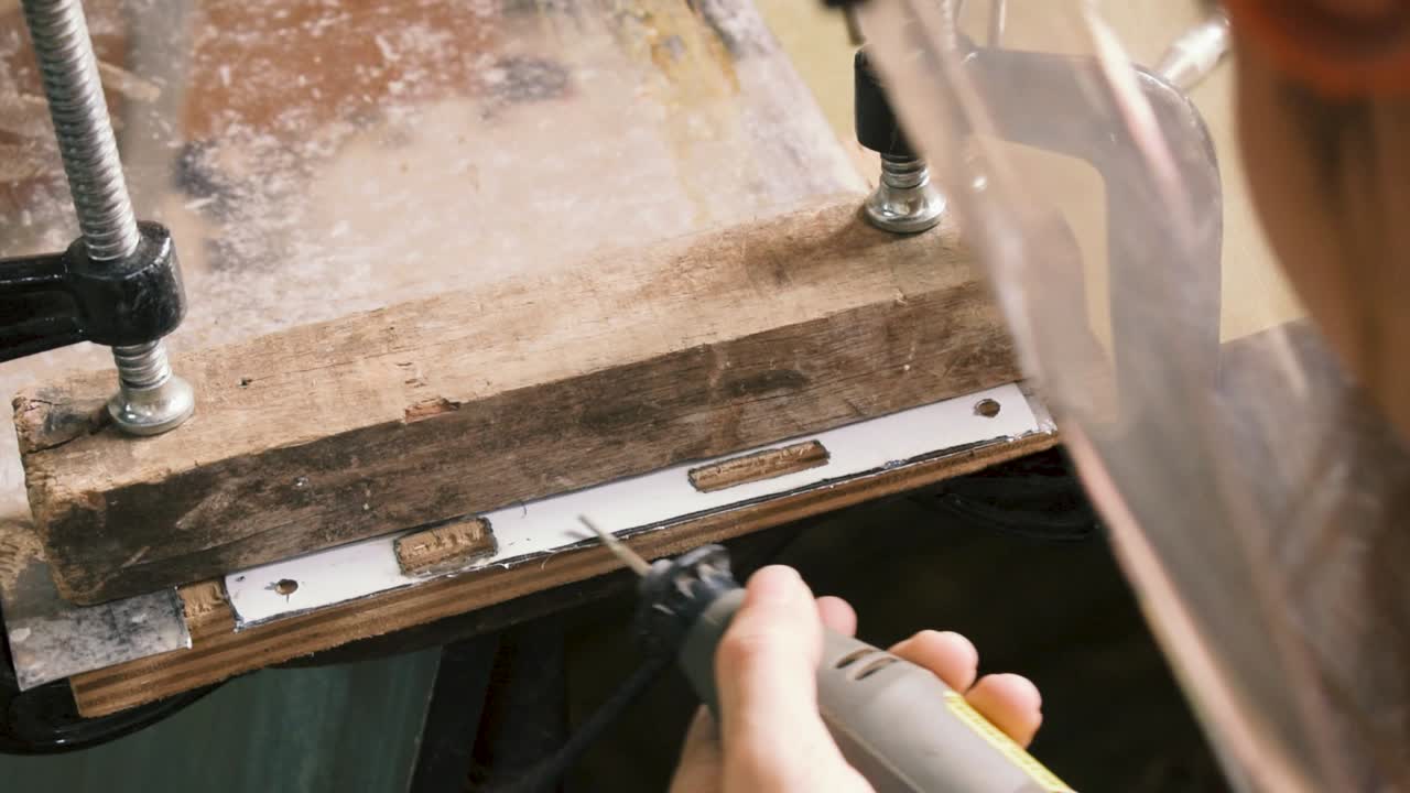 작은 다이 그라인더로 문 잠금 장치의 작은 금속 시트를 연마하는 여성