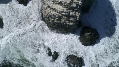 Drone-Descendiendo-A-Través-De-Imponentes-Acantilados-Con-Olas-Espumosas-En-Piedra-De-La-Piramide-En-Linares,-Chile