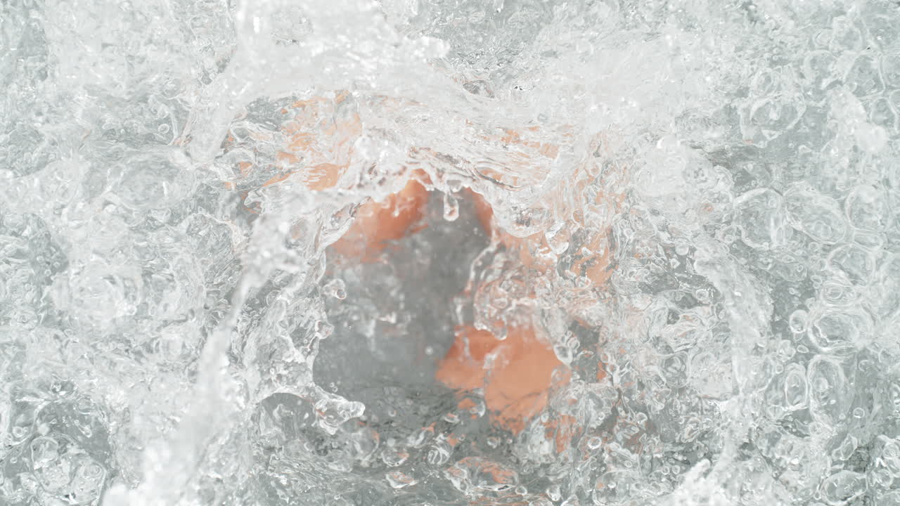 Eggs In Shells Falling Into Pot Of Boiling Water Making A Splash In Slow Motion, Table Top View