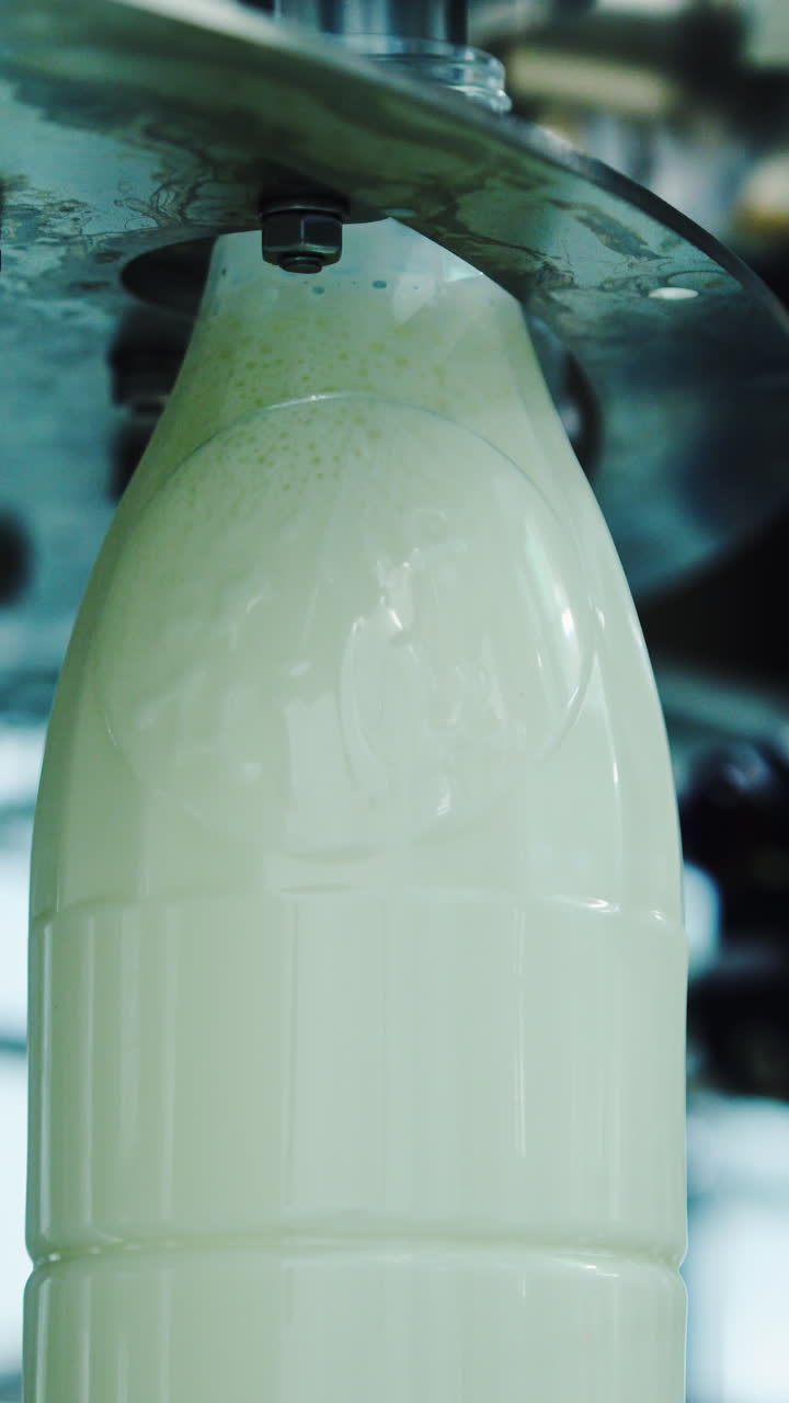 Milk is pouring into plastic bottles at a modern food factory. Footage of milk bottles at the production line in a milk company. Dairy production close-up. Vertical video