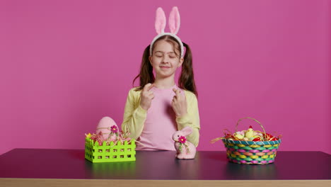 small cheerful kid posing with fingers crossed in studio