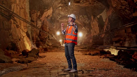 full body side view of asian male engineer with safety helmet screaming goal celebrating working in underground mine tunnel