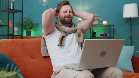 caucasian young man use laptop surprised by bad news, fortune loss, fail, lottery results at home