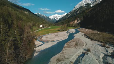 antena de un pintoresco río de montaña con agua azul fresca en los alpes bávaros austríacos por el sol de la tarde, fluyendo por un lecho de grava a lo largo de árboles, bosques y colinas vistos por un vuelo de drones desde arriba