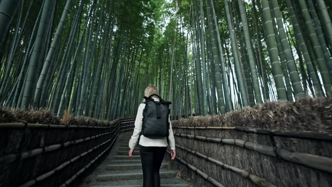 A young woman strolls through the mystical Arashiyama Bamboo Forest in Kyoto, Japan.