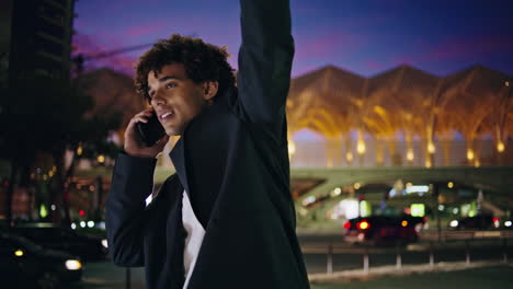 calling man peeping taxi at night town closeup. happy businessman waving hand