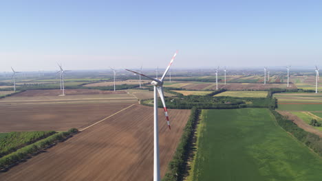 grand vista aerial of renewable energy wind farm turbines amongst farm land and crop fields