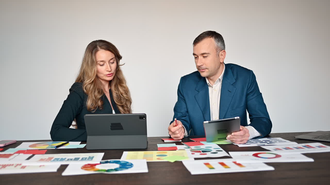 Coworkers talking while pointing at a tablet in an office