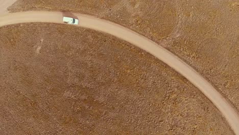 large van drives a curved dirt road on a fall day