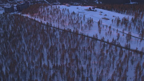 Impresionante-Toma-Aérea-Inclinada-Hacia-Arriba-De-Las-Pistas-De-Esquí-De-Levi-Al-Atardecer,-Kittila,-Finlandia