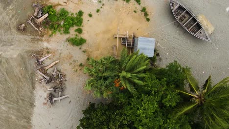 aerial flying over fisherman repairing fish nets besides traditional wooden boats on kuakata sea beach, bangladesh