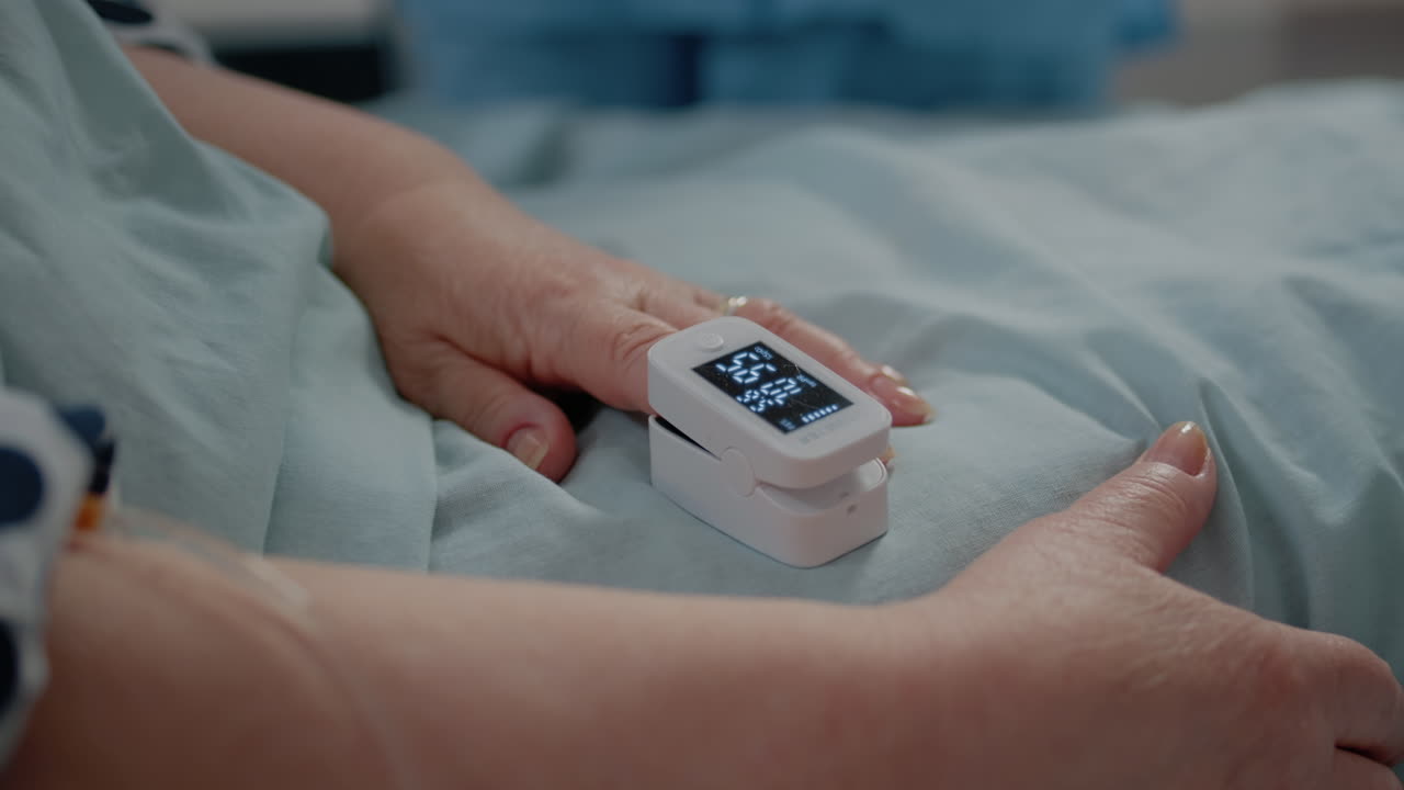 Close up of oximeter on finger showing low oxygen saturation