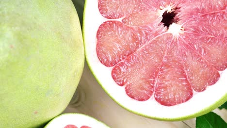 top view rotate red pomelo fruit with leaves on wooden table in garden, red pomelo fruit with leaves in wooden background 4k resolution.