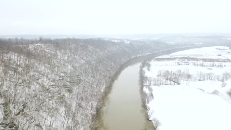 slow dolly aerial over brown kentucky ohio river in winter with snow all over the ground