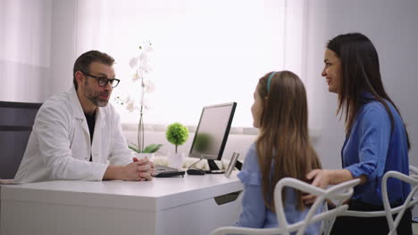 doctor consulting with a young patient and her mother in a clinic