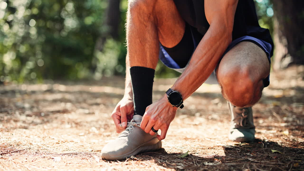 Uomo che si allaccia le scarpe prima di una corsa nel bosco