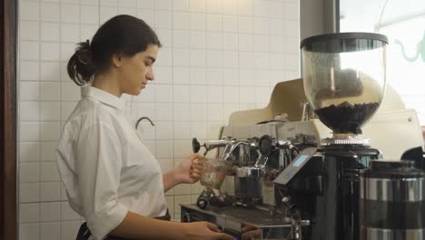 portrait of young middle east woman worker, barista in apron making a coffee by using coffee machine in kitchen bar of coffee shop. business service. people lifestyle.