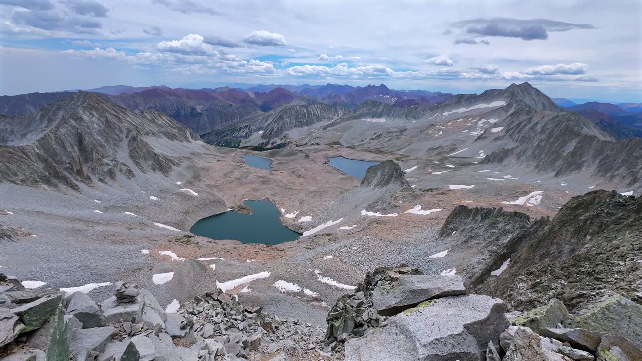 Capitol Peak 14er Wilderness high alpine elevation Rocky Mountains Colorado aerial drone Maroon Bells Peaks Mount Snowmass Knifes Edge Ridge Pierre Lakes summer early morning blue sky cloudy pan left