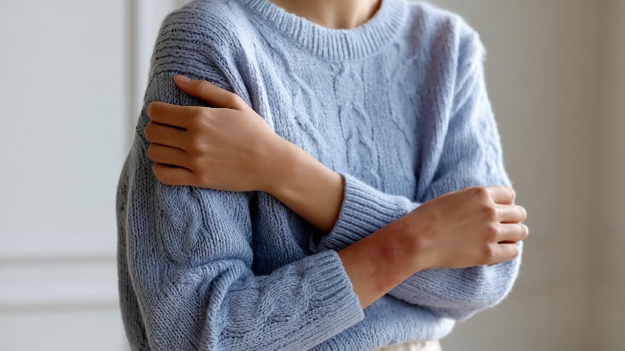 Una scena accogliente: un primo piano di una persona che si abbraccia con un morbido maglione blu, evocando sensazioni di calore, comfort e introspezione in un ambiente interno discreto.