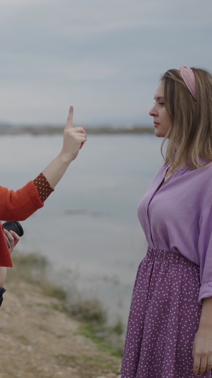 Two women standing outdoors near a lake