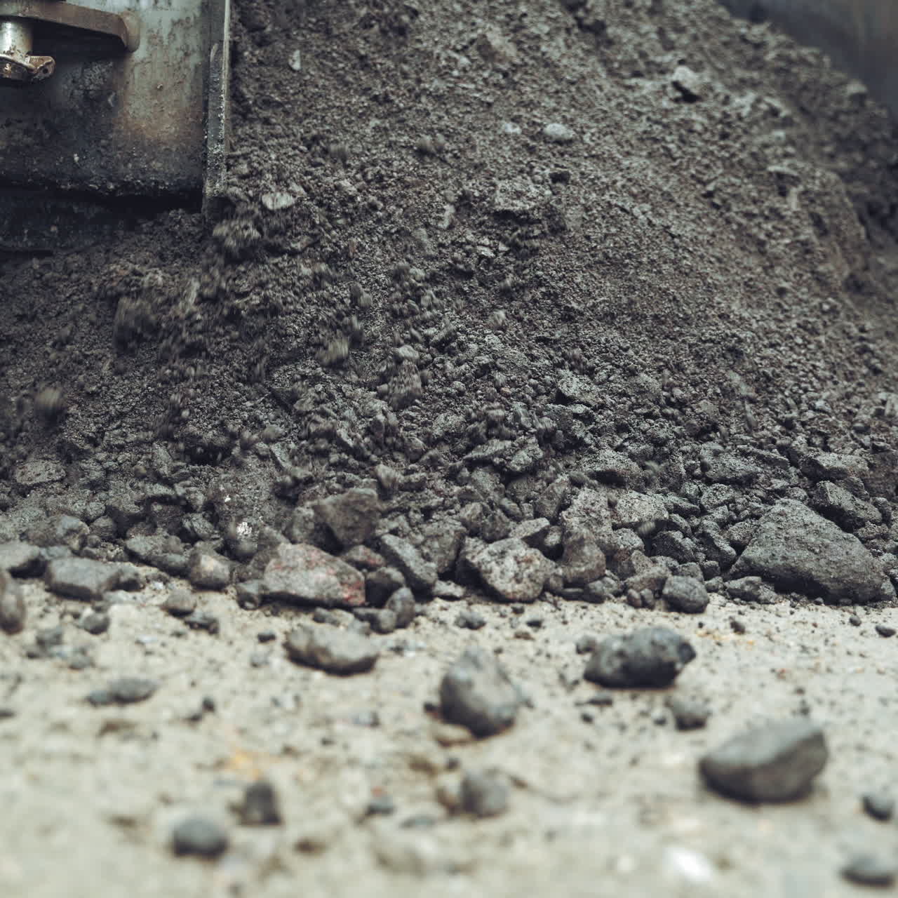 Process of pouring hot asphalt out off the heavy machine into the ground. Roadworks repaving process. Close-up
