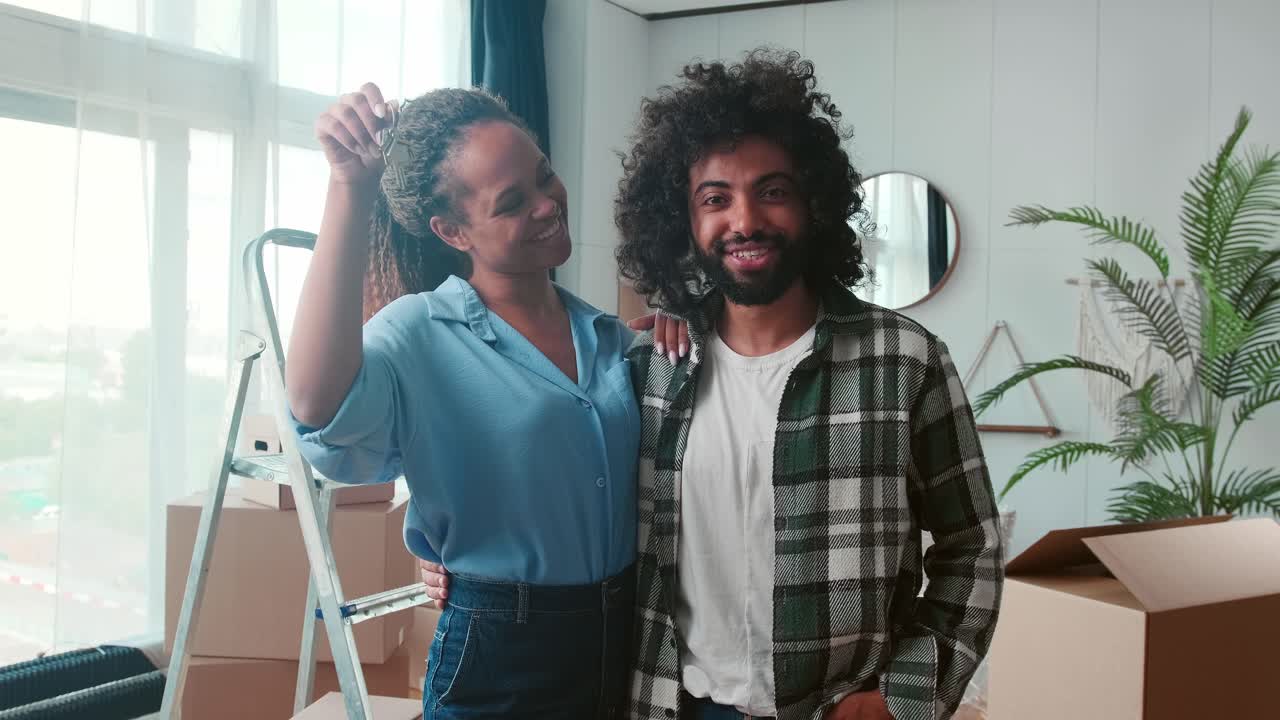 joven contento familia multirracial hombre y mujer de pie en casa mostrar llaves